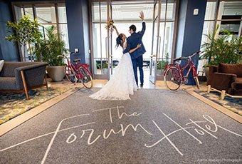 bride and groom from behind ealking out of Kimpton Forum Hotel entrance