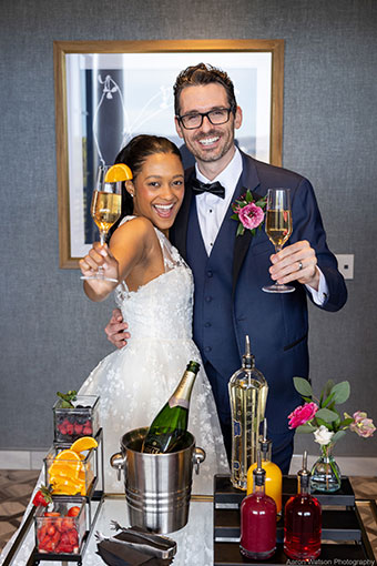 bride and groom holding up champagne glasses for camera