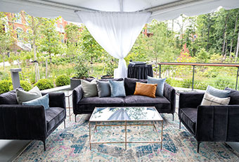 Couches and seating under a tent with view of botanical garden at Kimpton Forum Hotel